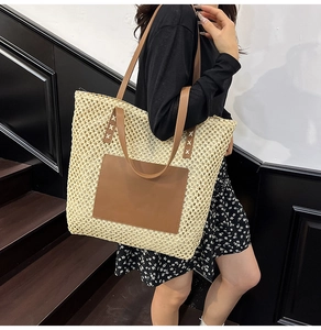 Detail of cross-stitched leather pocket on large straw tote bag with shoulder straps