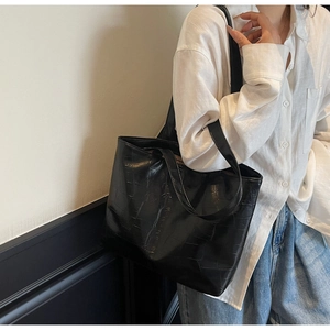 Detail of black crocodile texture tote bag showing premium matte finish and draping style