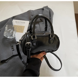 Detailed view of black patent leather Boston bag with white branding and shiny finish