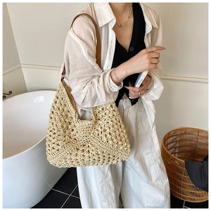 Detail view of woven straw shoulder bag featuring textured knit and brown leather strap