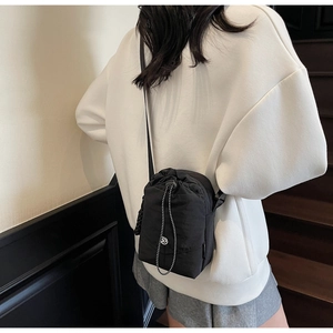 Détail du sac seau noir à cordon avec bandoulière réglable et logo métallique en D
