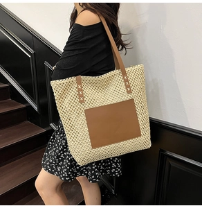 Detail of the woven texture and brown faux leather pocket on a straw tote bag