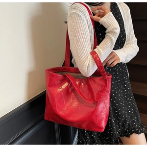 Detail of red crocodile pattern tote bag shown with model for size and texture reference