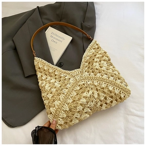 Close-up of woven fan-shaped texture and brown leather strap on summer straw tote bag