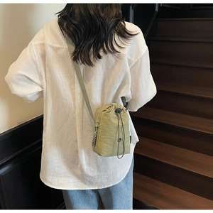 Détail du sac à cordon en nylon vert sauge avec fermeture éclair latérale et tirette tissée