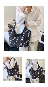 Detail of summer bucket bag featuring white floral embroidery and black ribbon bow accent