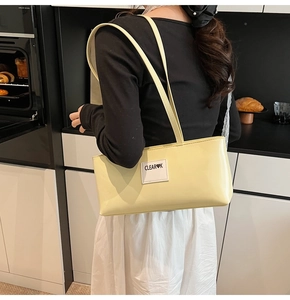 Detail der glänzenden Lackleder Baguette Tasche in Hellgelb mit CLEAR K Logo-Aufnäher