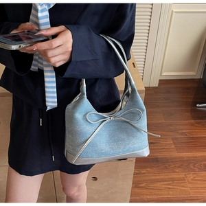 Dettaglio borsa a spalla in denim con fiocco argento e manico con finitura a specchio