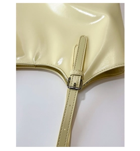 Détail de la bandoulière de sac jaune crème brillant avec boucle en métal argenté et coutures