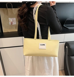 Gelbe Leder-Umhängetasche mit weißem CLEAR-Logo und doppelten Riemen in Detailansicht