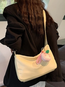 Minimalist light yellow hobo bag with peach charm and wide shoulder strap for women