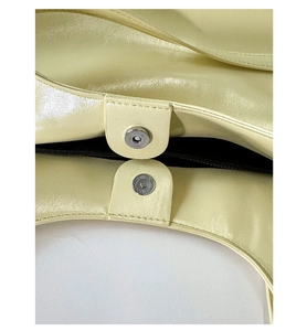 Vue détaillée de la fermeture magnétique et texture du cuir fin sur un sac crème