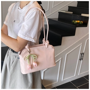 Dettaglio della borsa tote rosa chiaro con ciondolo a tulipano e tracolla con nodi