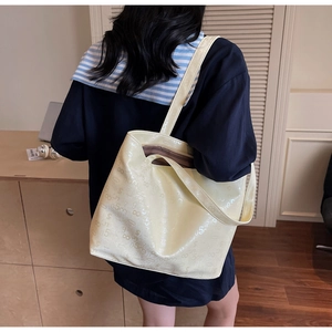 Detail of large creamy yellow tote bag with embossed pattern and wide shoulder strap