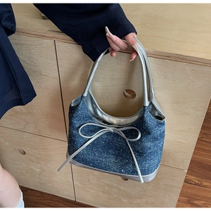 Dettaglio borsa sottobraccio in denim con fiocco argento e decorazioni in cristallo