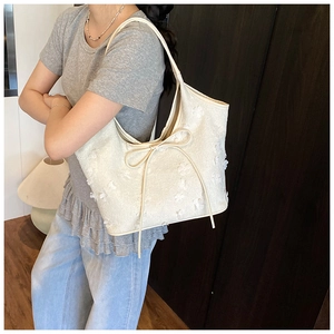 Close-up of beige pleated tote bag featuring 3D floral textures and a slender bow detail