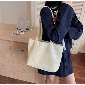 Detail of light beige tote bag featuring embossed number textures and sturdy dual handles