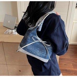 Dettaglio borsa sottobraccio in denim blu con paillettes e fiocco specchio argento