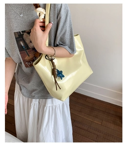 Détail du cabas en cuir verni jaune pâle avec pendentif étoile et breloque tissée
