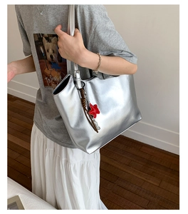 Détail du sac cabas argenté métallisé avec breloque étoile rouge et pompon en cuir marun