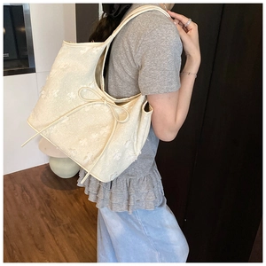Detail of creamy tote bag with 3D floral texture and elegant bow on the shoulder