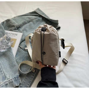 Détail du sac bandoulière en nylon beige pour bouteille avec cordon noir et sangle large