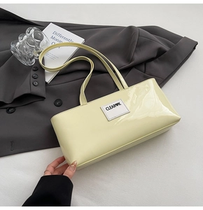 Detailansicht der cremefarbenen Lackleder-Tasche mit Clear K-Logo und doppelten Trägern