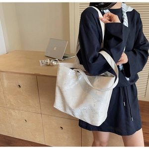 Detailed view of cream white tote bag with numeric print on a shoulder strap model
