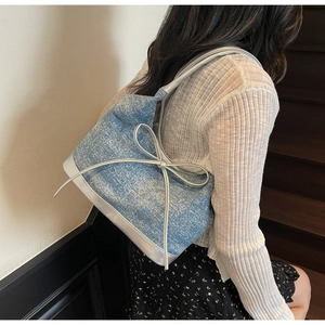Dettaglio della borsa a spalla in denim blu con strass scintillanti e decorazione a fiocco