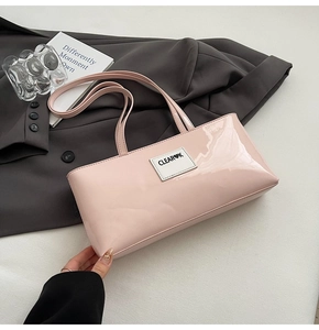 Detailansicht der hellrosa Lackleder-Schultertasche mit Glanzeffekt auf grauem Blazer