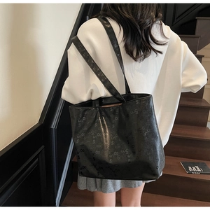 Close-up of black glossy tote bag with stylish numeric patterns and sturdy shoulder straps