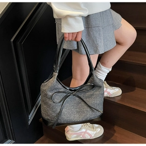 Dettaglio della borsa denim con grande fiocco nero e pois su scale in legno vintage