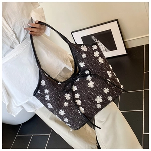 Close-up of large black tweed tote bag featuring white floral patches and bow details