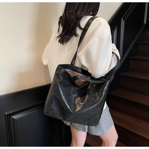 Model back view showing large capacity black tote bag with embossed letter patterns
