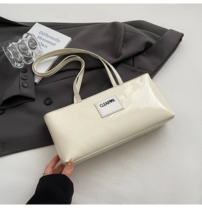 Detailansicht einer cremeweißen Lacklederhandtasche mit minimalistischem Herz-Logo