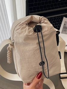 Sac seau minimaliste en nylon beige avec fermeture à cordon et bandoulière large
