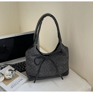Vista dettagliata della borsa in denim grigio a pois con finiture in pelle e fiocco