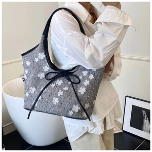 Detail of grey tweed tote bag featuring 3D white flower motifs and black ribbon bow