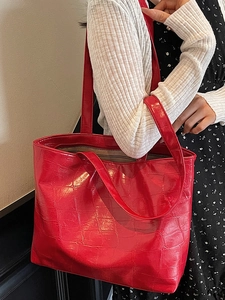 Large red crocodile pattern tote bag shown on a model with a stylish casual outfit