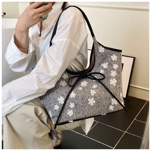 Detail of grey tweed bucket bag featuring 3D white flower appliqués and black leather trim