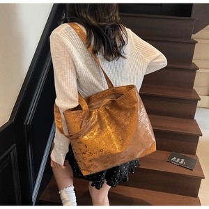 Detail of metallic bronze large tote bag with all-over print shown in lifestyle setting