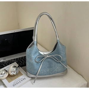 Dettaglio borsa in denim con fiocco argento e finiture in pelle metallizzata