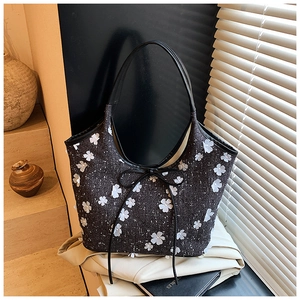 Detail of elegant black tweed bucket bag with white floral 3D appliques and ribbon bow