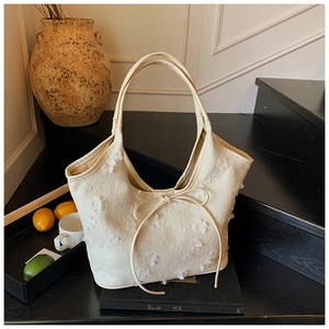 Detail of cream canvas tote bag featuring 3D floral petals and elegant bow tie accents