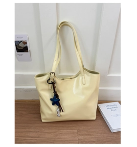 Détail du sac fourre-tout jaune crème montrant le cuir PU lisse et le pendentif