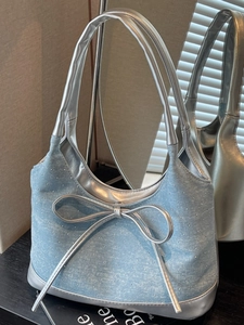 Borsa hobo in denim azzurro con fiocco argento e strass su una superficie nera