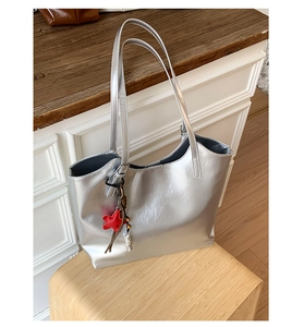 Détail du sac cabas argenté avec breloque étoile rouge et bandoulière perlée sur une chaise