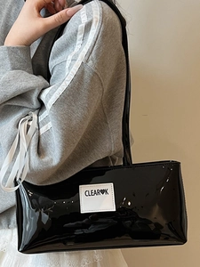 Minimalistische schwarze Lackleder-Schultertasche mit Logo-Label an einem weiblichen Model