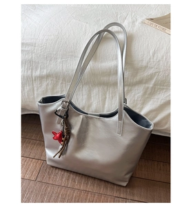 Détail d'un sac cabas argenté métallisé avec breloque étoile rouge et pompon en cuir