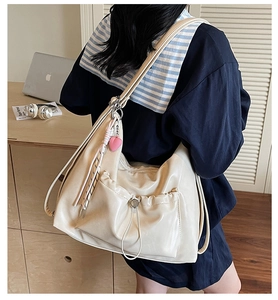 Detail of beige large capacity tote bag featuring pleated texture and heart charm